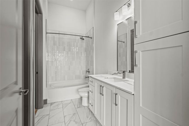 Bathroom with shower / bath combo with shower curtain, vanity, toilet, and marble finish floors | Image 17