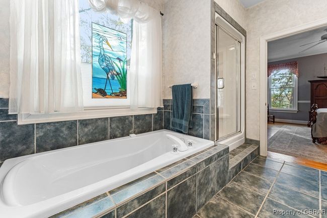 Bathroom featuring a bath, a shower with shower door, ceiling fan, and tile patterned floors | Image 28