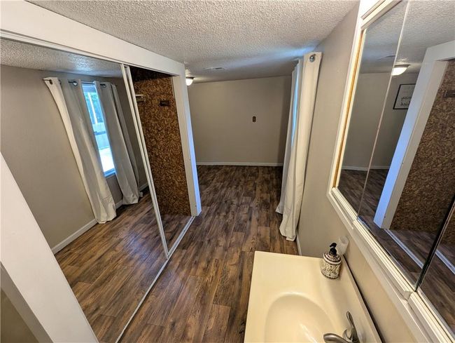 Bathroom featuring a textured ceiling, wood finished floors, baseboards, and vanity | Image 19