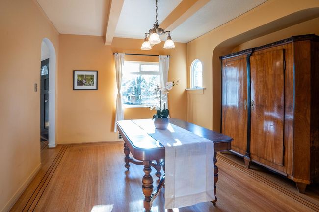 Dining room with a notable chandelier, baseboards, arched walkways, beamed ceiling, and light wood-style floors | Image 6