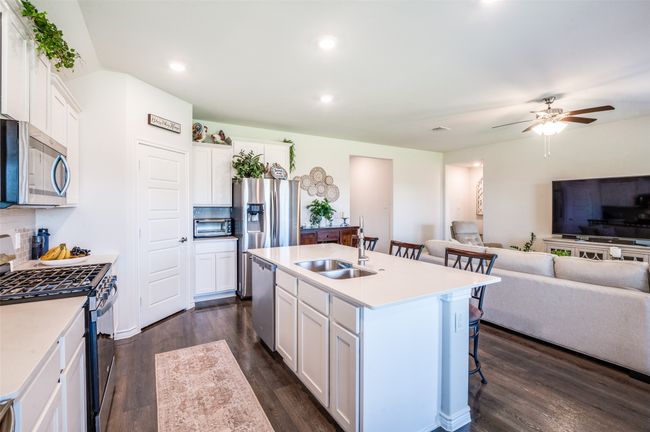 Kitchen featuring appliances with stainless steel finishes, open floor plan, a breakfast bar, dark wood finished floors, and white cabinets | Image 10