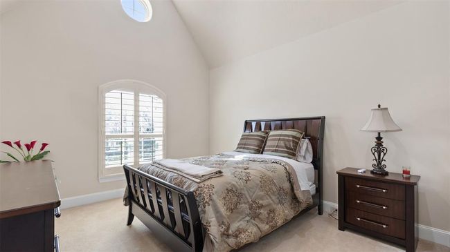Sun-filled upstairs bedroom features plush carpet, plantation shutters, vaulted ceilings and a dainty circular window for the occasional daydreamer. | Image 40
