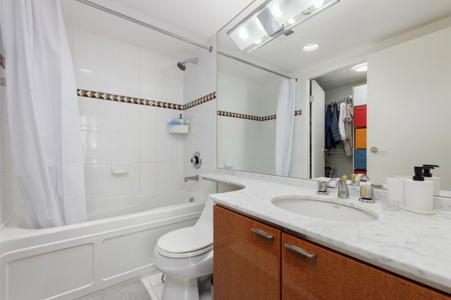 Bathroom with vanity, shower / bath combination with curtain, toilet, and tile patterned flooring | Image 9