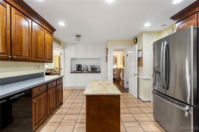 Kitchen with stainless steel fridge, dishwasher, light tile patterned floors, recessed lighting, and a kitchen island | Image 14