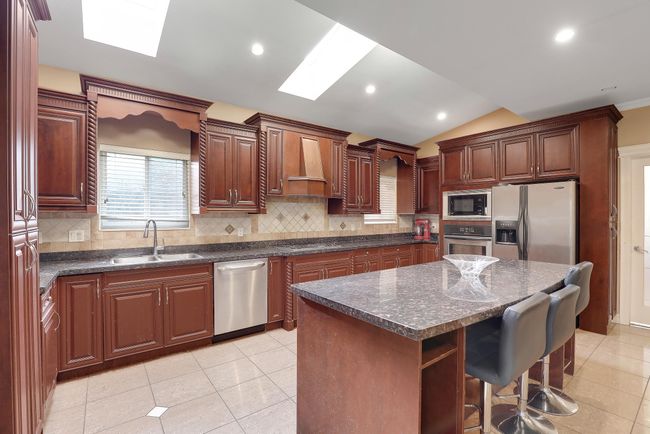 Kitchen featuring a breakfast bar area, tasteful backsplash, stainless steel appliances, and a sink | Image 17