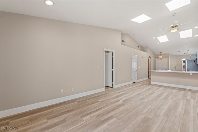 Unfurnished living room featuring light wood-style flooring, ceiling fan, recessed lighting, a skylight, and arched walkways | Image 6