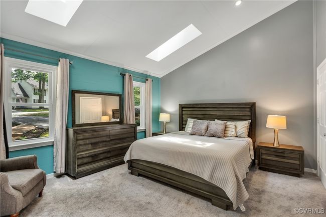 Bedroom featuring a skylights, vaulted ceiling, crown molding, multiple windows, carpet, walk-in-closet, ensuite | Image 16