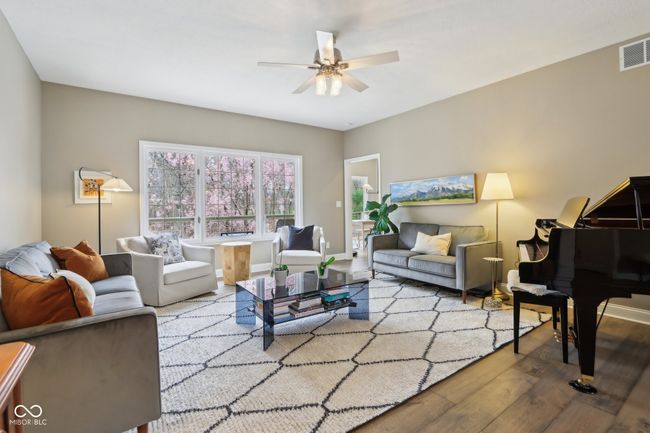 living room featuring a ceiling fan, wood finished floors, baseboards, and visible vents | Image 11