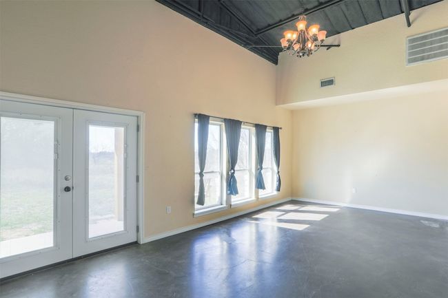 Empty room featuring french doors, visible vents, finished concrete floors, a chandelier, and baseboards | Image 10