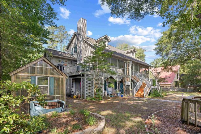 Back of property with a greenhouse, stairway, a chimney, an outbuilding, and a sunroom | Image 33