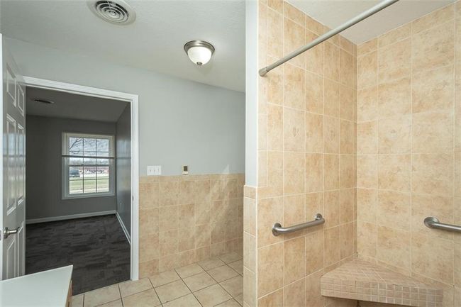 Bathroom featuring visible vents, a wainscoted wall, a tile shower, tile patterned floors, and tile walls | Image 25