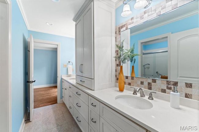 Full bathroom featuring double vanity, a shower stall, ornamental molding, and tile patterned flooring | Image 30