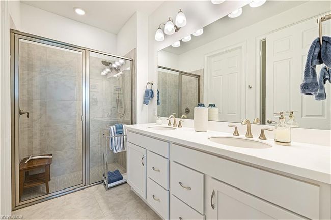 Bathroom with double vanity, a stall shower, and tile patterned flooring | Image 19