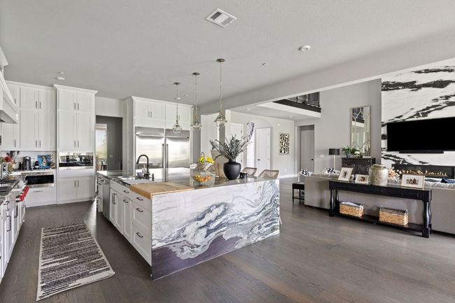 Kitchen with visible vents, white cabinets, a sink, open floor plan, and appliances with stainless steel finishes | Image 11