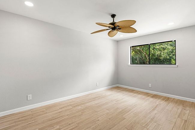 Empty room with a ceiling fan, light wood finished floors, and recessed lighting | Image 26