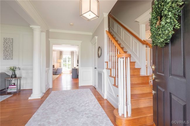 Entryway with decorative columns, a decorative wall, light wood-style floors, and crown molding | Image 6