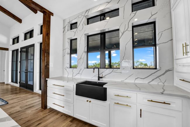 Kitchen with white cabinetry, light wood-style flooring, backsplash, and a sink | Image 10