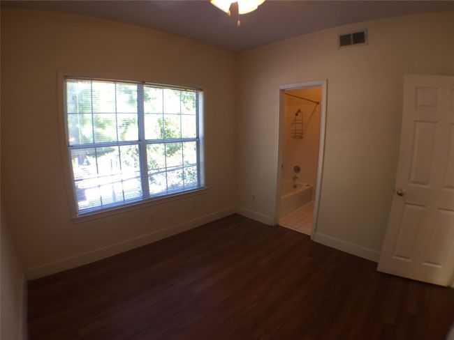 Empty room with baseboards, a ceiling fan, dark wood-type flooring, and visible vents | Image 6