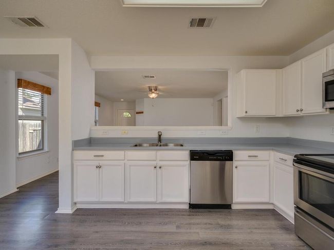 Kitchen featuring appliances with stainless steel finishes, white cabinets, luxury vinyl wood-look flooring, and light countertops. | Image 11