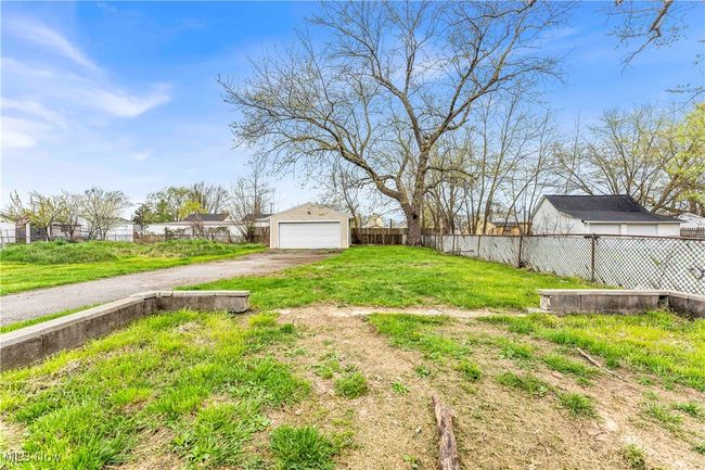 View of yard featuring an outbuilding, driveway, a garage, and fence | Image 23
