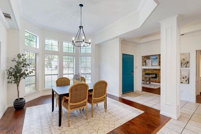 Dining area with hardwood / wood-style flooring, a chandelier, ornate columns, ornamental molding, and a fireplace | Image 14