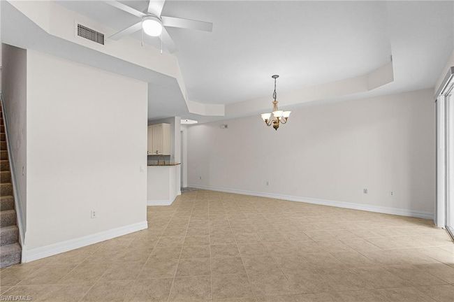 Unfurnished living room featuring a chandelier, stairs, a raised ceiling, ceiling fan, and light tile patterned flooring | Image 11