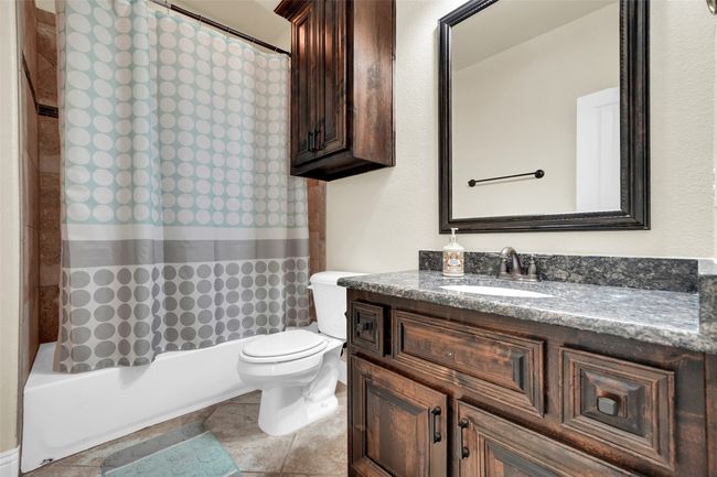 Bathroom with vanity, shower / bathtub combination with curtain, and light tile patterned flooring | Image 36