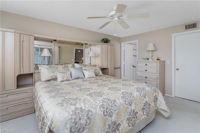 Bedroom featuring light colored carpet, ceiling fan, a textured ceiling, and visible vents | Image 13