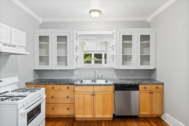 Kitchen with dishwasher, white range with gas stovetop, a sink, under cabinet range hood, and dark wood-style floors | Image 8