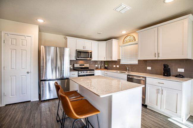 Kitchen with stainless steel appliances, dark wood-style flooring, a kitchen island, backsplash, and recessed lighting | Image 9
