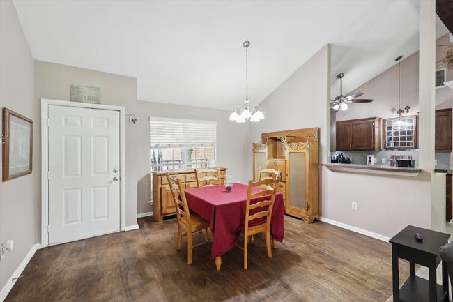 Dining room featuring ceiling fan with notable chandelier, baseboards, and dark wood-type flooring | Image 7