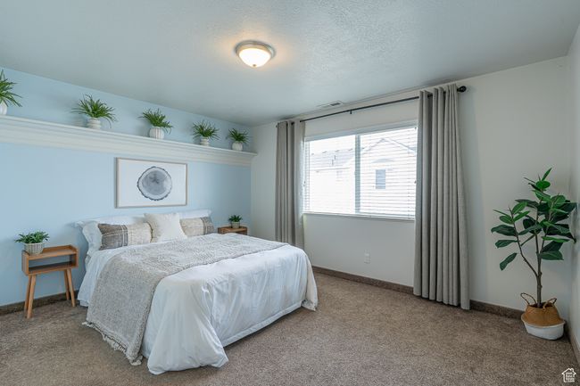 Bedroom featuring baseboards, visible vents, light colored carpet, and a textured ceiling | Image 14