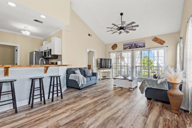 Living area with visible vents, wood finished floors, ornamental molding, and a ceiling fan | Image 4
