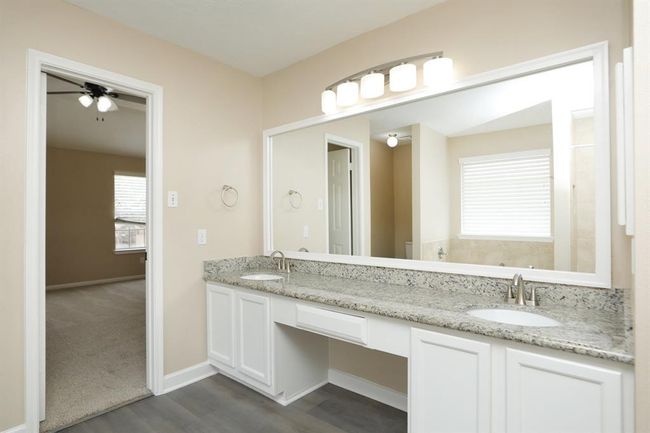 Double sink vanity with updates including light fixtures, granite counters and framed mirror. | Image 25