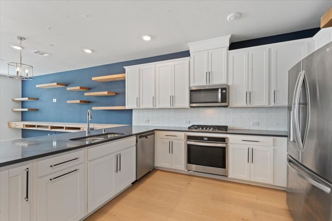 Kitchen featuring light wood-type flooring, white cabinetry, sink, and stainless steel appliances | Image 19
