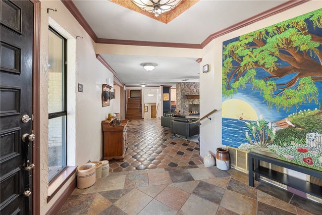 Foyer featuring stairs, a fireplace, ornamental molding, and stone tile flooring | Image 9
