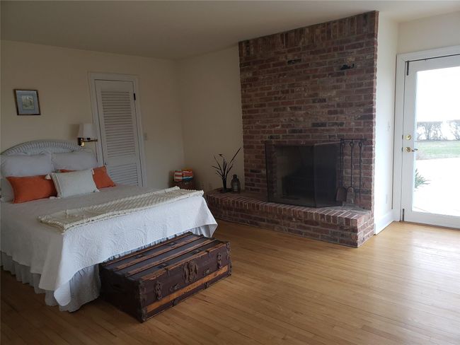 Bedroom with light wood-style flooring, a brick fireplace, and access to exterior | Image 21