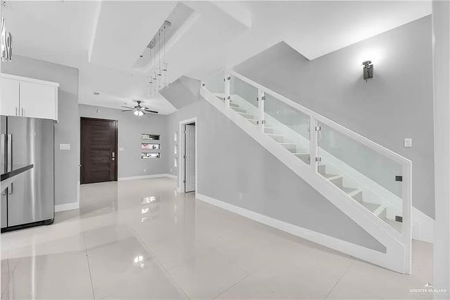Unfurnished living room featuring stairway, light tile patterned floors, and ceiling fan | Image 8