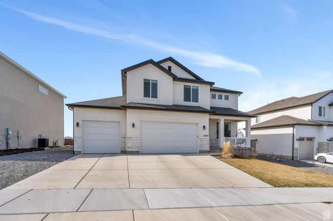 View of front of property featuring concrete driveway, stucco siding, central AC unit, a garage, and covered porch | Image 42