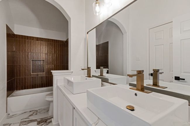 Full bathroom with double vanity, marble finish flooring, and shower / washtub combination | Image 22