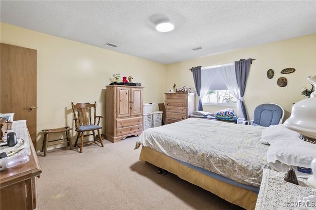 Bedroom featuring light colored carpet, a textured ceiling, and visible vents | Image 10