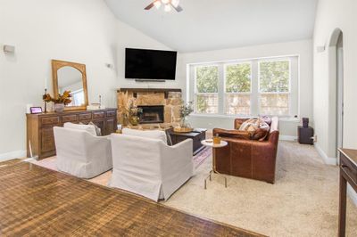 Carpeted living room with high vaulted ceiling, ceiling fan, and a stone fireplace | Image 2