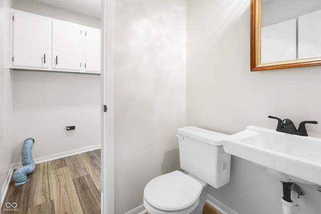 half bath featuring baseboards, wood finished floors, toilet, and a sink | Image 12