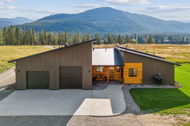 View of front of house with a mountain view, concrete driveway, a front lawn, metal roof, and a garage | Image 6