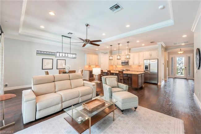 Living area with a raised ceiling, crown molding, a ceiling fan, baseboards, and dark wood-style floors | Image 13