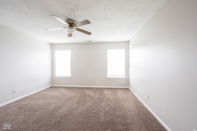 carpeted spare room featuring baseboards, a textured ceiling, ceiling fan, and a healthy amount of sunlight | Image 30