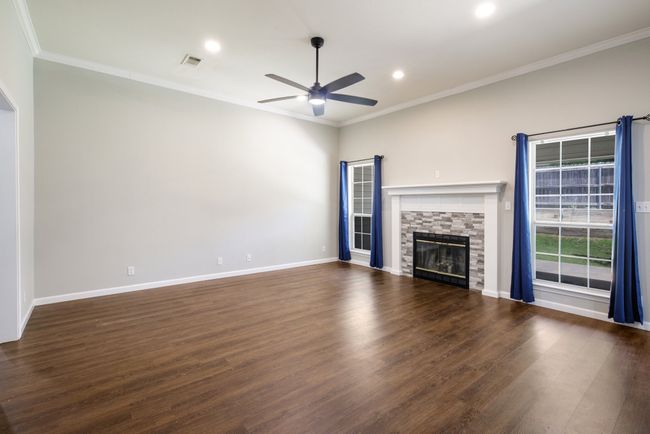 Unfurnished living room with a ceiling fan, crown molding, recessed lighting, wood finished floors, and a fireplace | Image 26