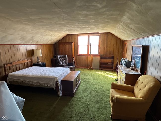 bedroom featuring light carpet, lofted ceiling, and wooden walls | Image 31