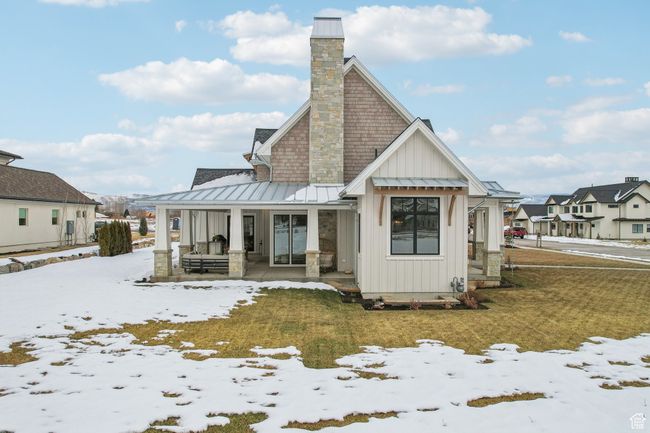 Snow covered house with a chimney, a porch, board and batten siding, a standing seam roof, and metal roof | Image 66
