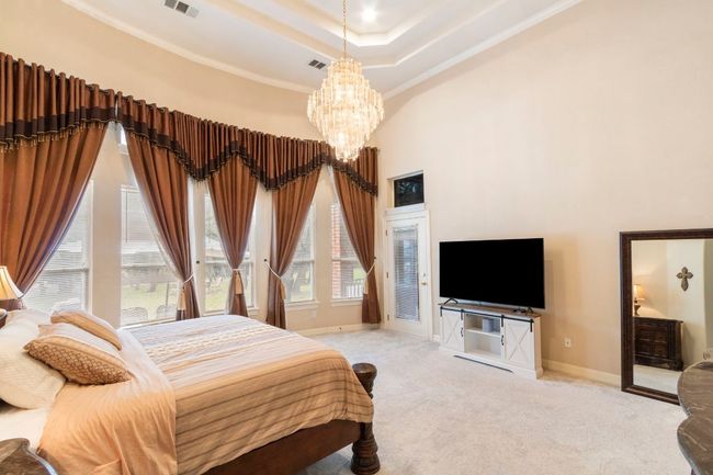 Bedroom with a chandelier, baseboards, a high ceiling, carpet, and ornamental molding | Image 22